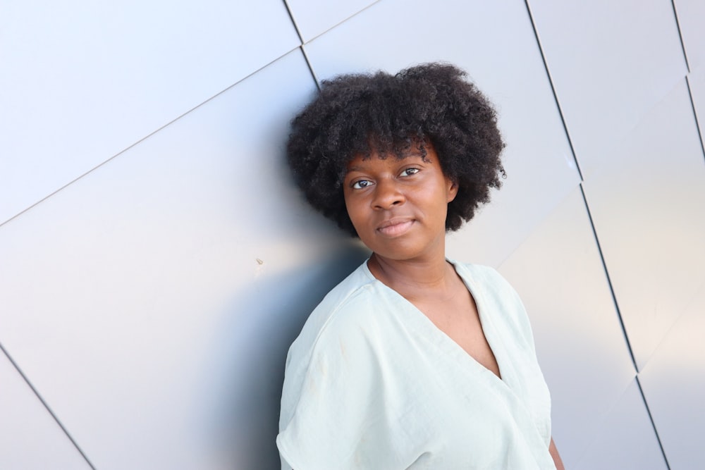 a woman with an afro standing against a wall