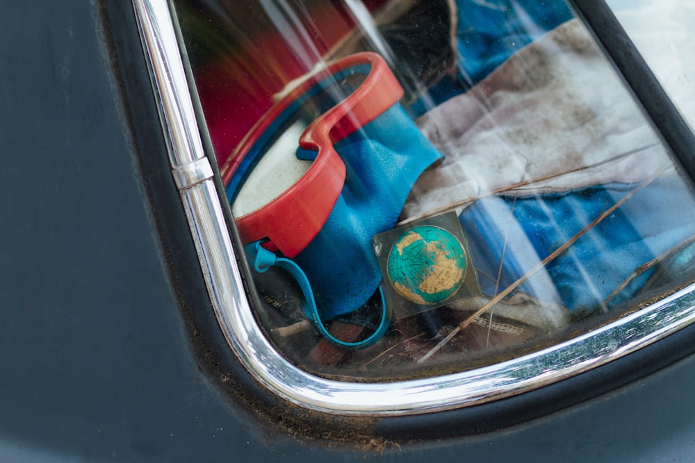 a reflection of a blue car with a red bucket