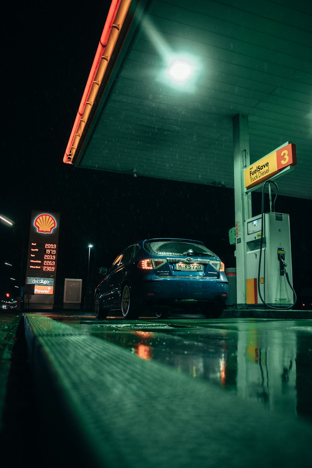 a blue car at a gas station at night