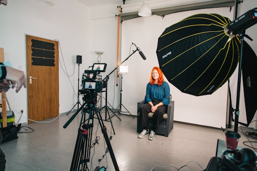 a woman sitting in a chair in front of a camera