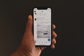 a hand holding a cell phone with twitter on the screen