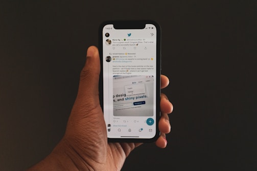 a hand holding a cell phone with twitter on the screen