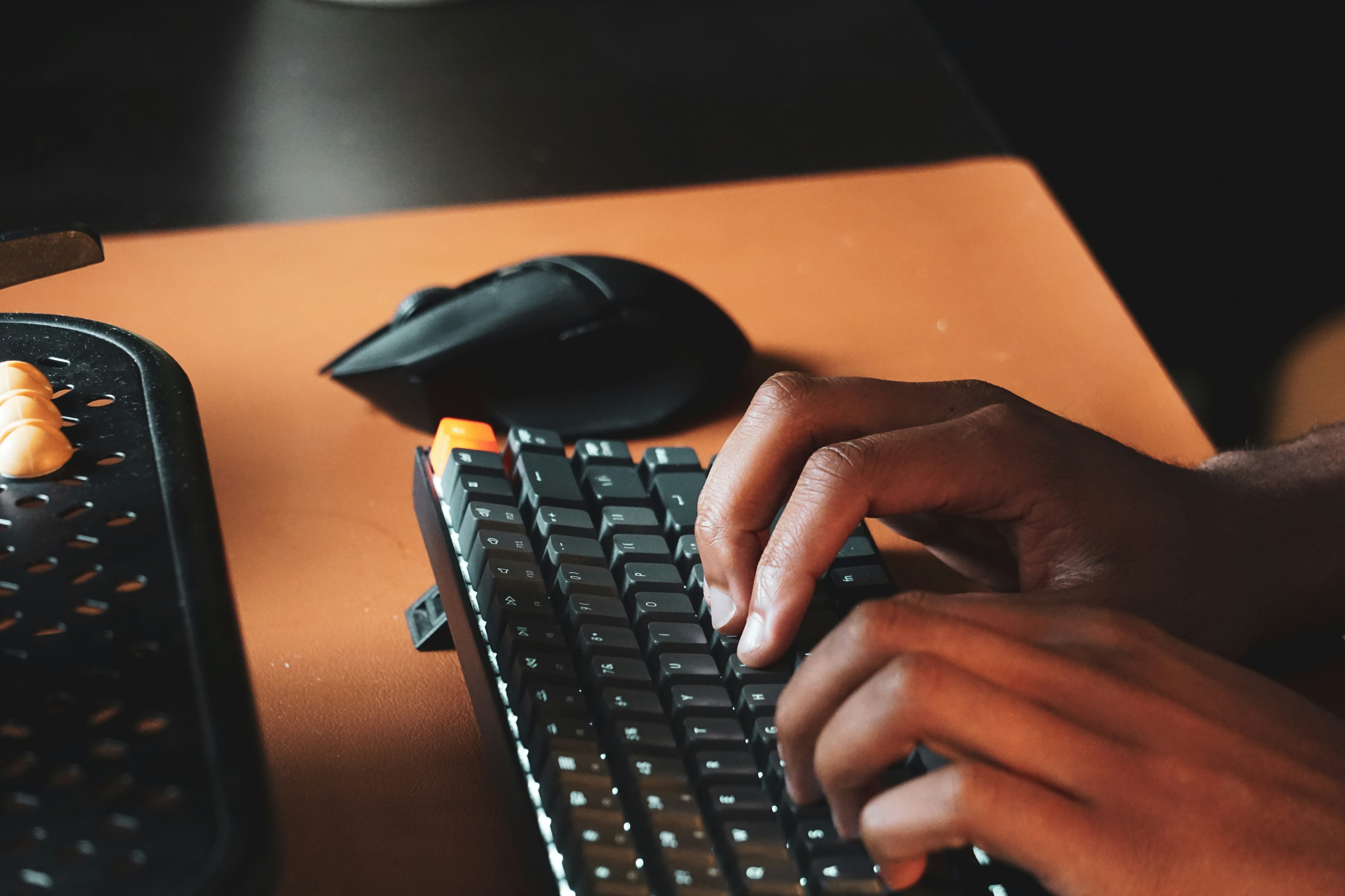 person typing on a mechanical keyboard in front of a dual monitor setup running Windows