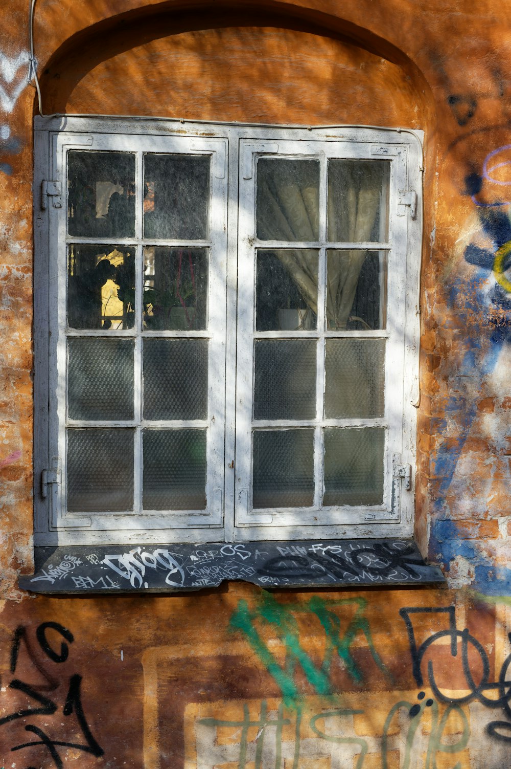uma janela em uma parede de tijolos com grafite sobre ela