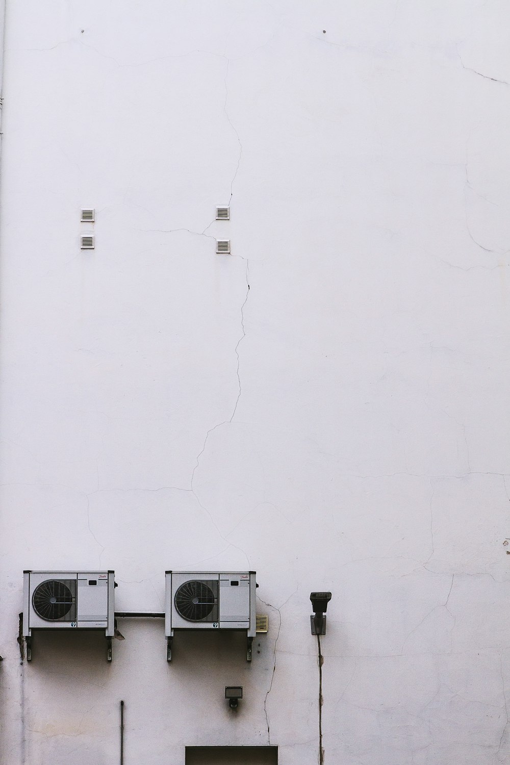 a white wall with three air conditioners on it