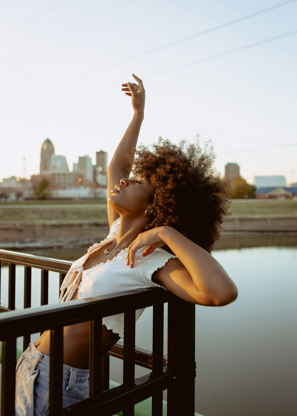 a woman leaning on a rail next to a body of water