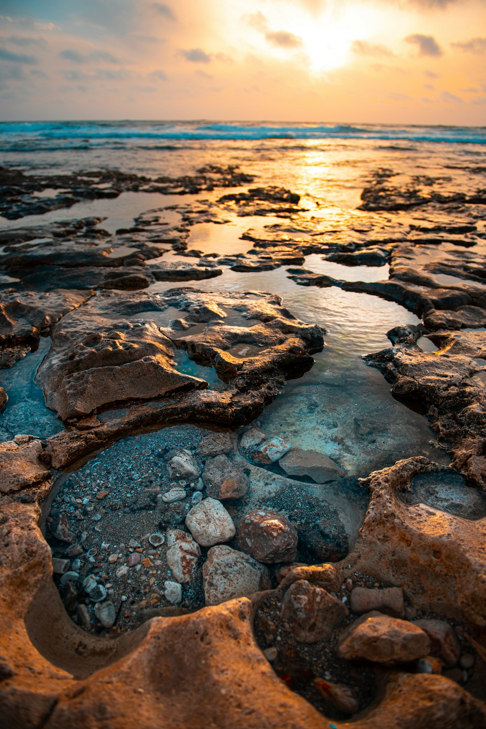 the sun is setting over a rocky beach