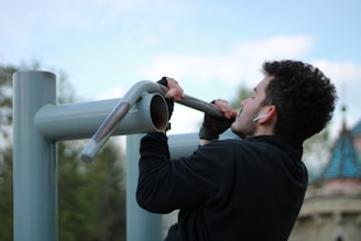 a man in a black jacket holding onto a metal pole