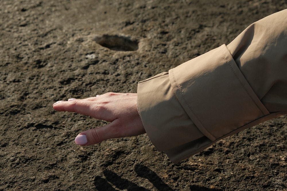 a person holding their hand out in the dirt