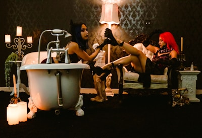 a couple of women sitting next to each other in front of a bath tub