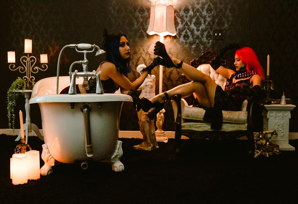 a couple of women sitting next to each other in front of a bath tub