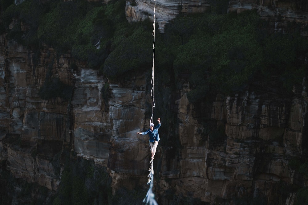 a man is hanging from a rope above a body of water