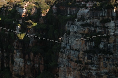 a man walking across a rope over a canyon