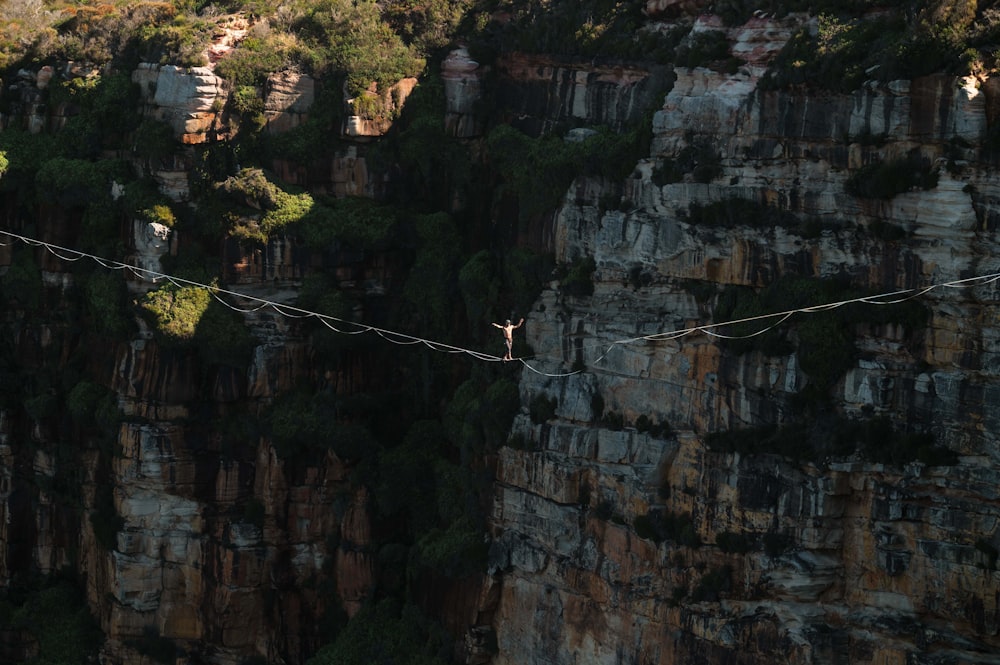 a man walking across a rope over a canyon