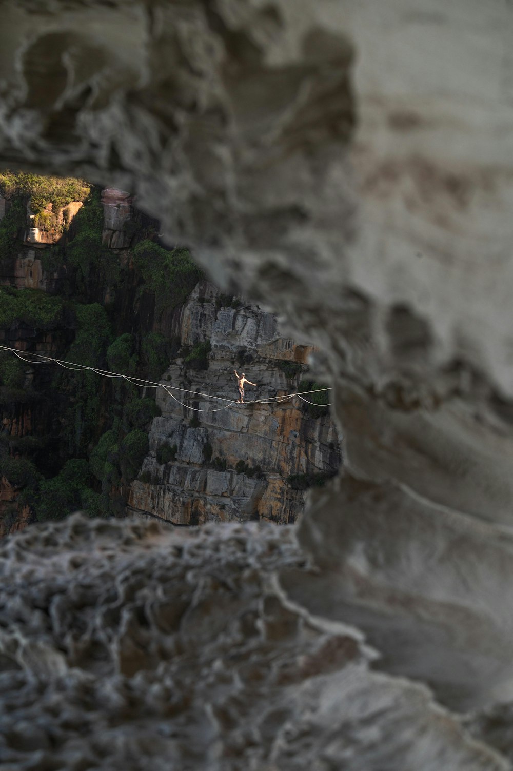 a man walking across a rope over a cliff