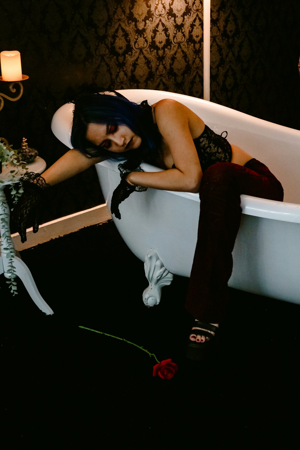 a woman sitting in a bathtub with a rose in her hand