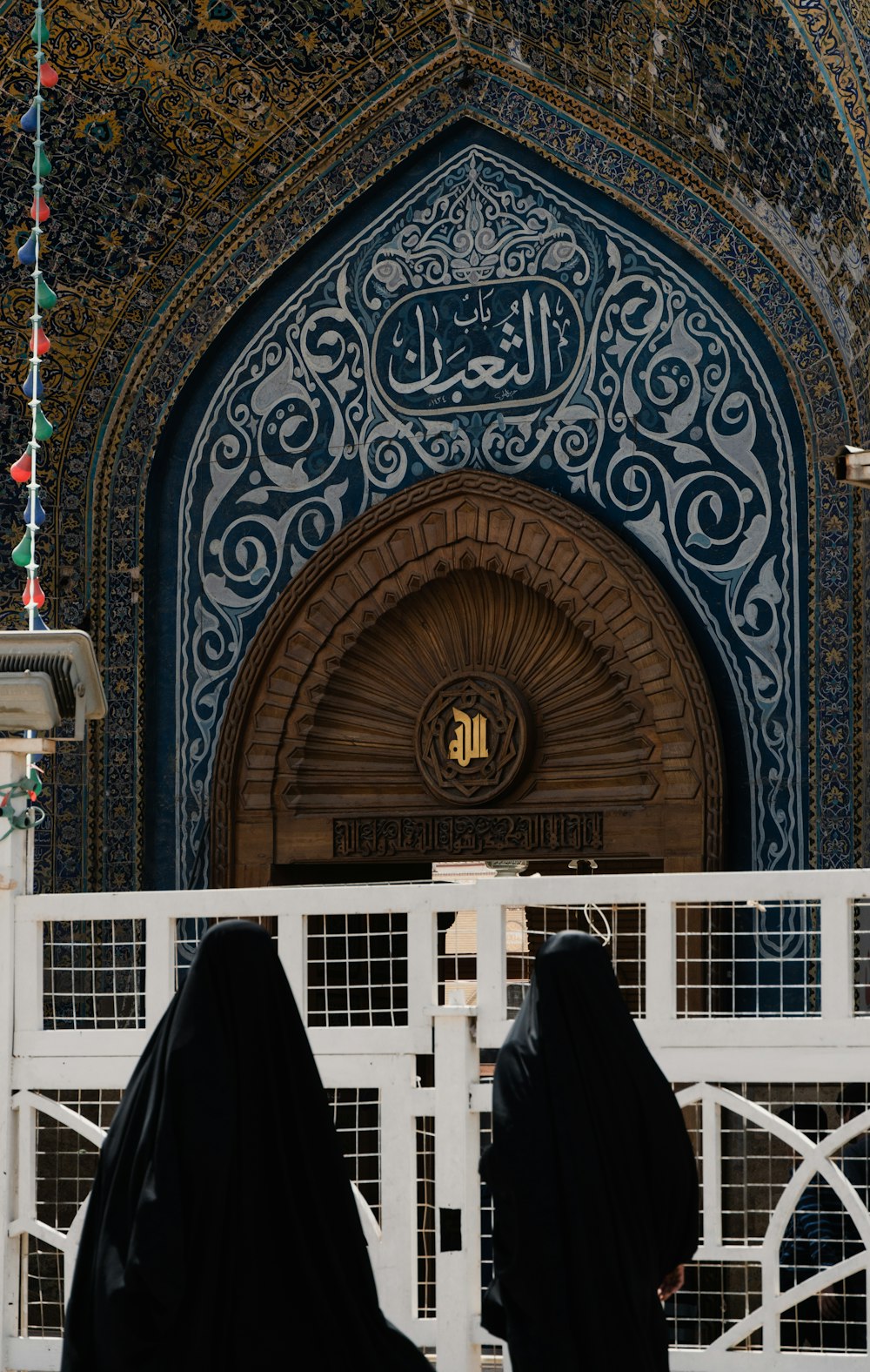two women in black robes are standing in front of a building