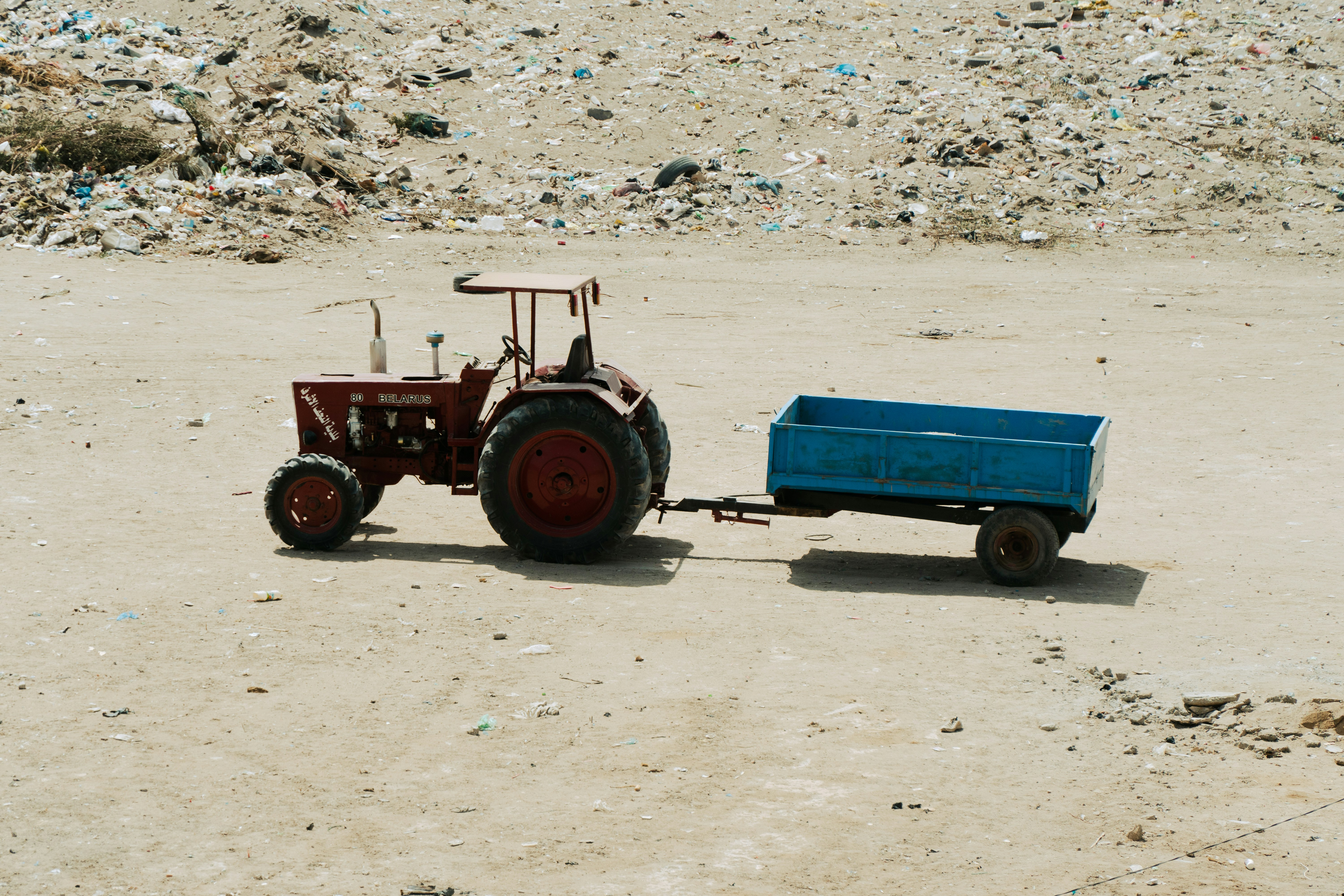 a tractor pulling a trailer behind it on a dirt field