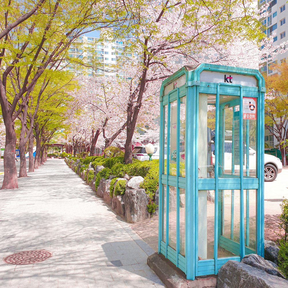 a blue phone booth sitting on the side of a road