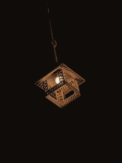 A hanging woven lamp illuminates the darkness, casting a warm glow. The lamp features a geometric pattern made from natural materials, possibly bamboo or rattan, and is suspended by a sturdy cord.