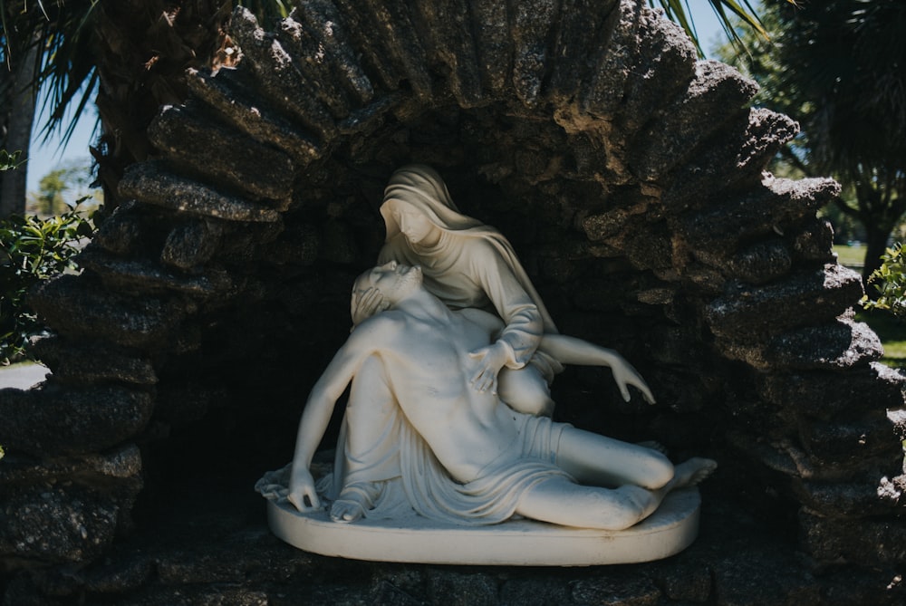 a statue of a woman laying on top of a stone wall