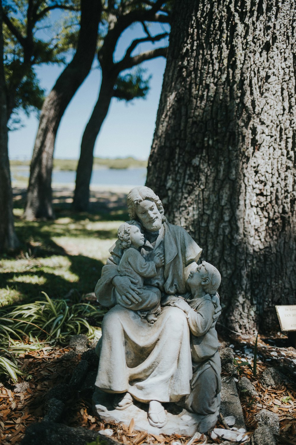 a statue of a woman holding a child under a tree