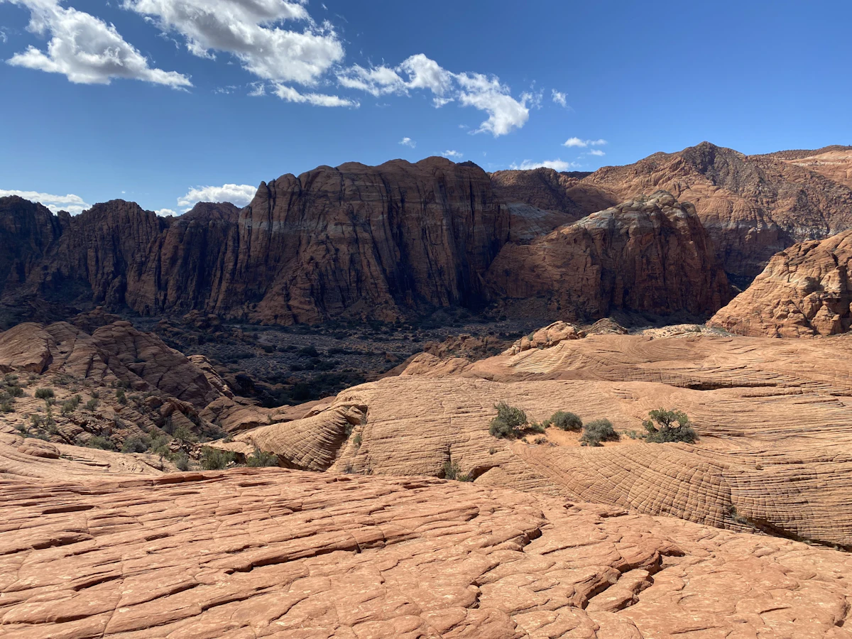 Swirled sandstone slickrock below red cliffs in Snow Canyon State Park, near Ivins