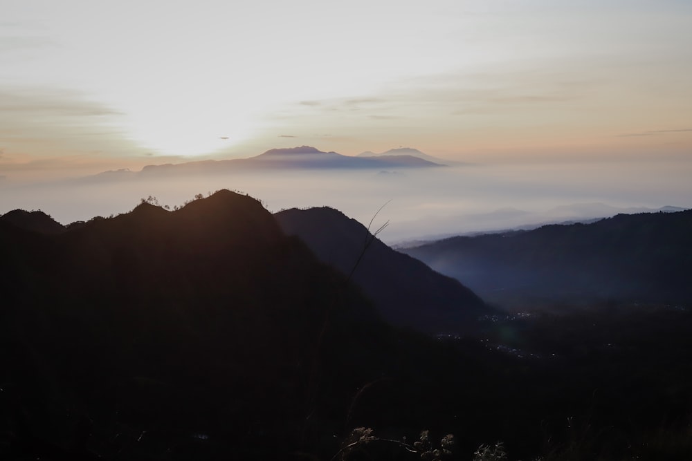 the sun is setting over a mountain range