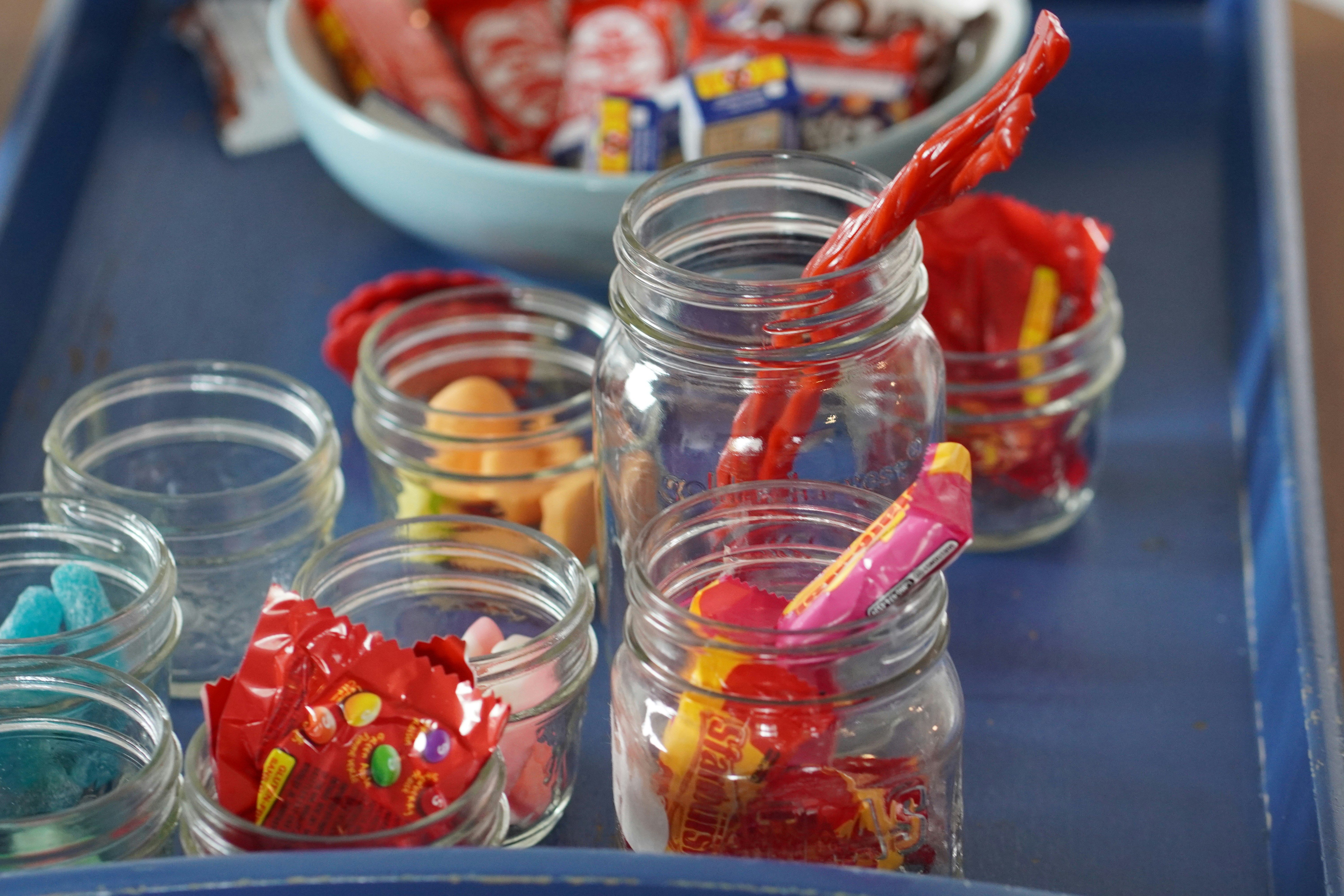 a blue tray topped with glass jars filled with candy