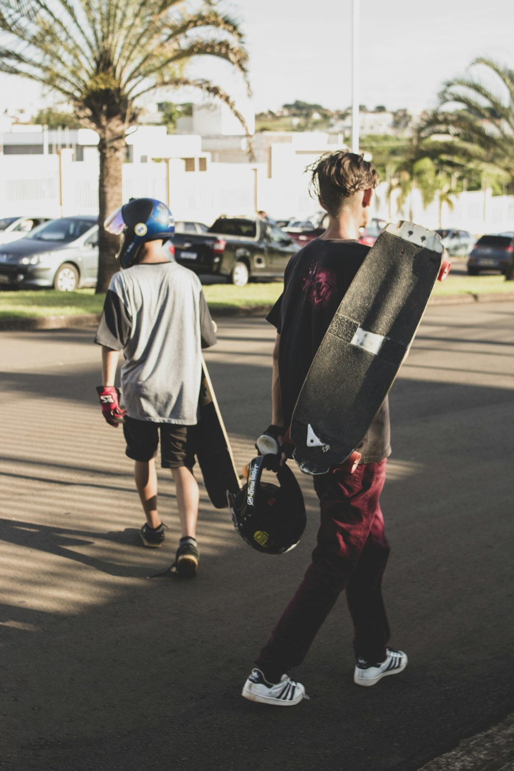 a boy carrying a skateboard while walking down a street