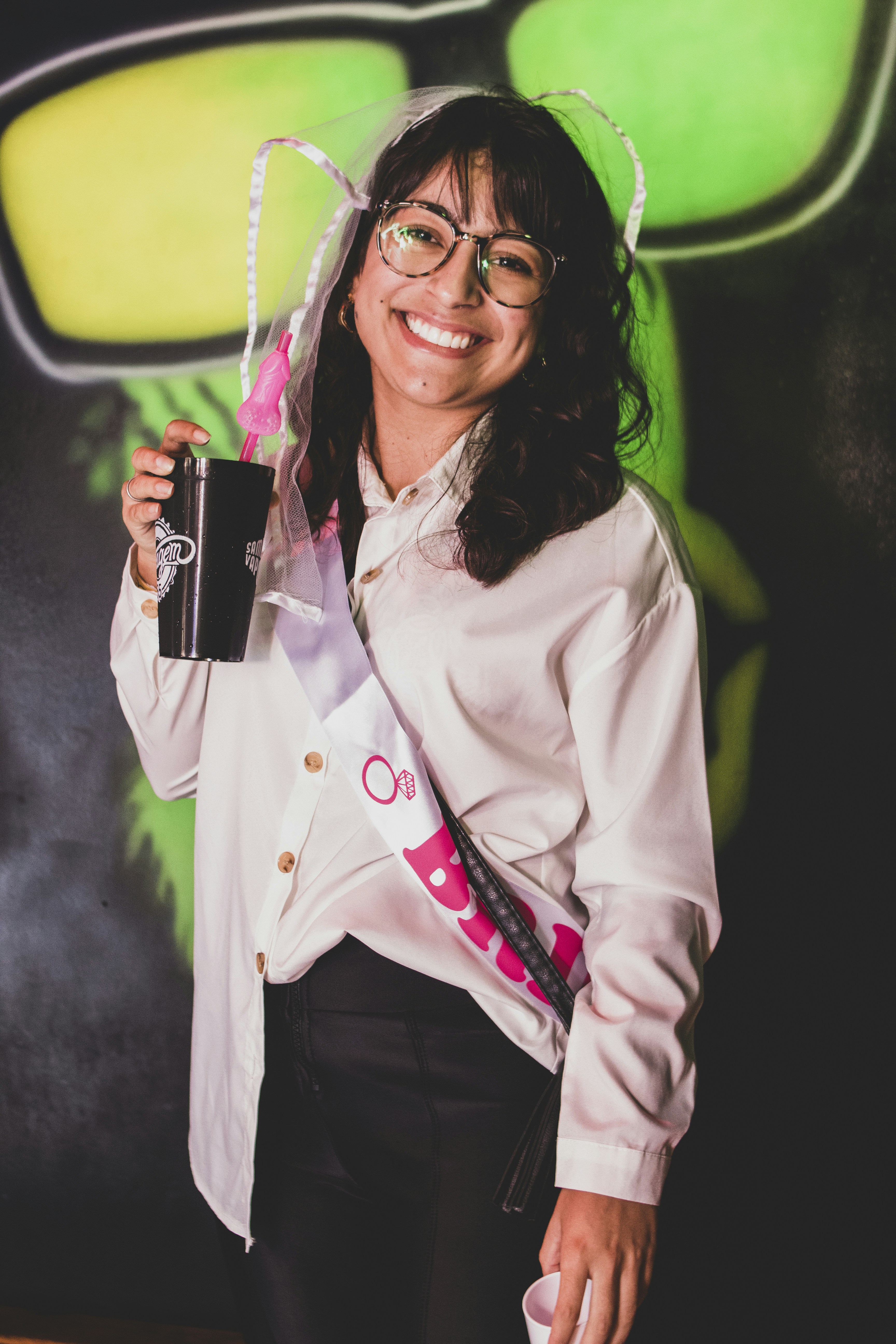 Seorang wanita dengan kemeja putih dan celana hitam memegang kamera