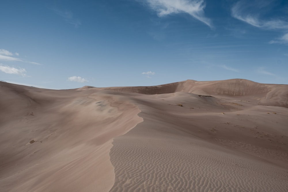 a desert landscape with sand dunes and a blue sky