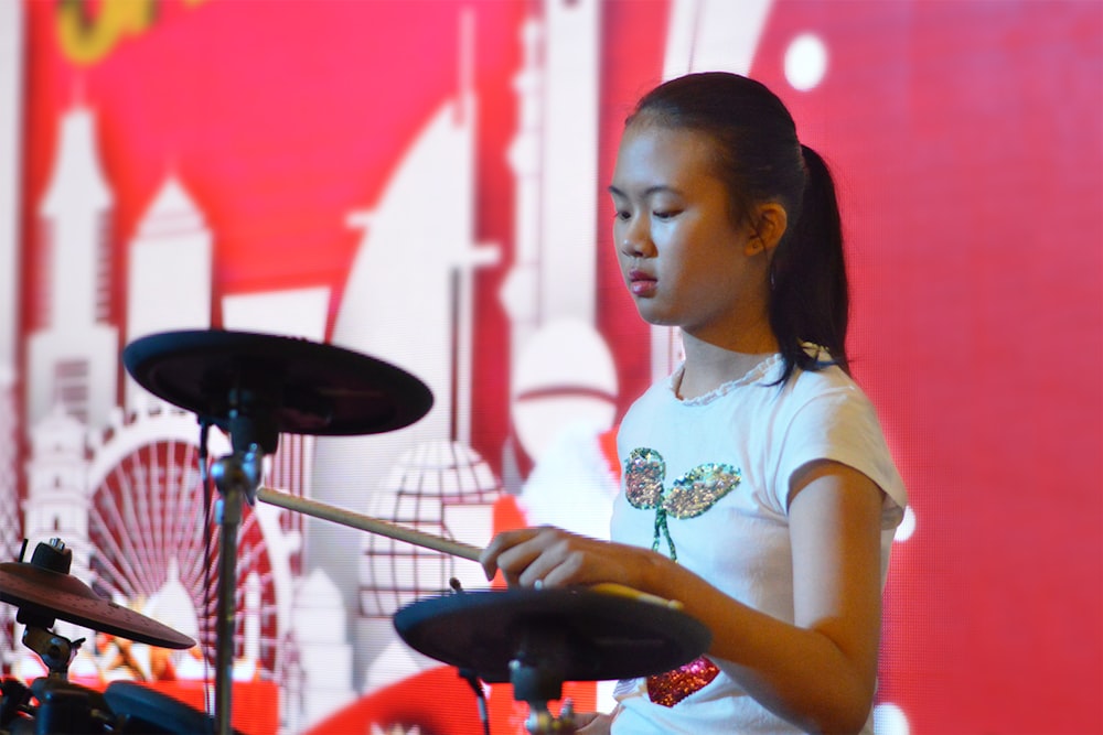 Una ragazza che suona la batteria davanti a un muro rosso foto – Umano  Immagine gratuita su Unsplash