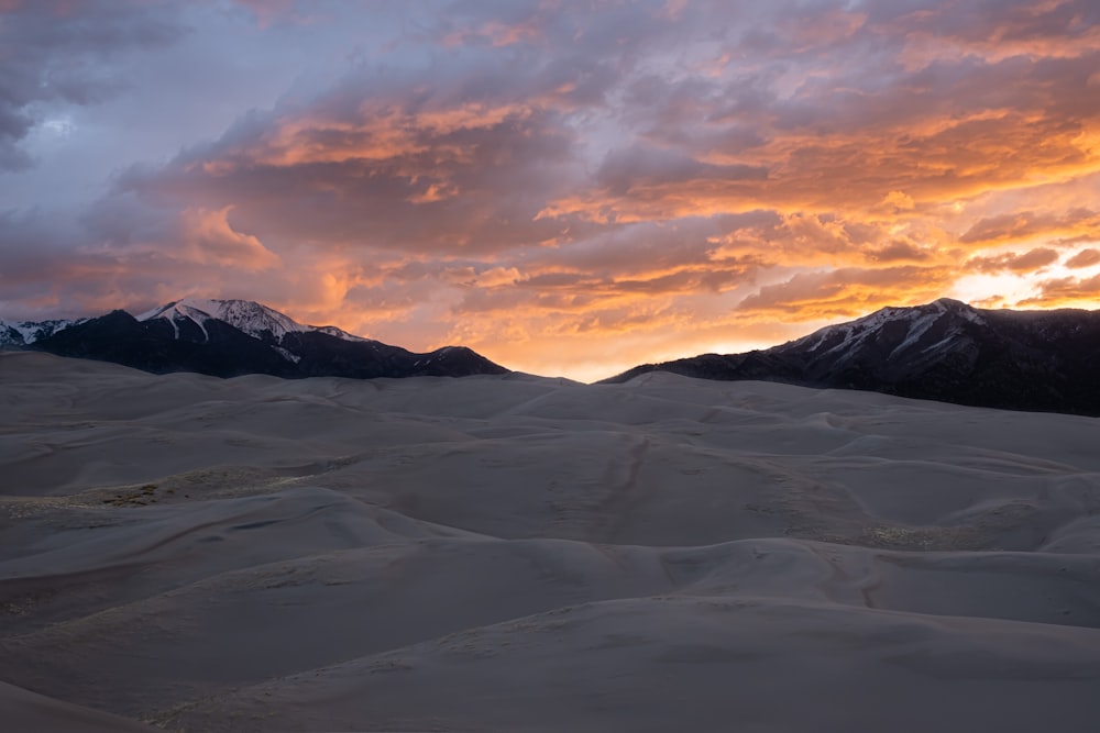 the sun is setting over the mountains in the desert