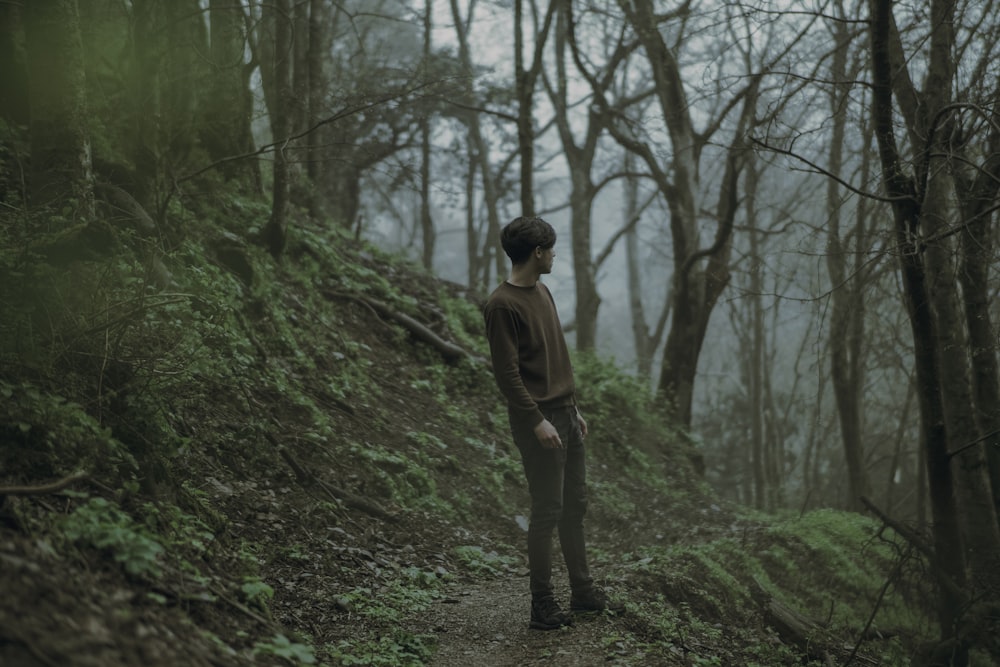 a man standing on a trail in the woods