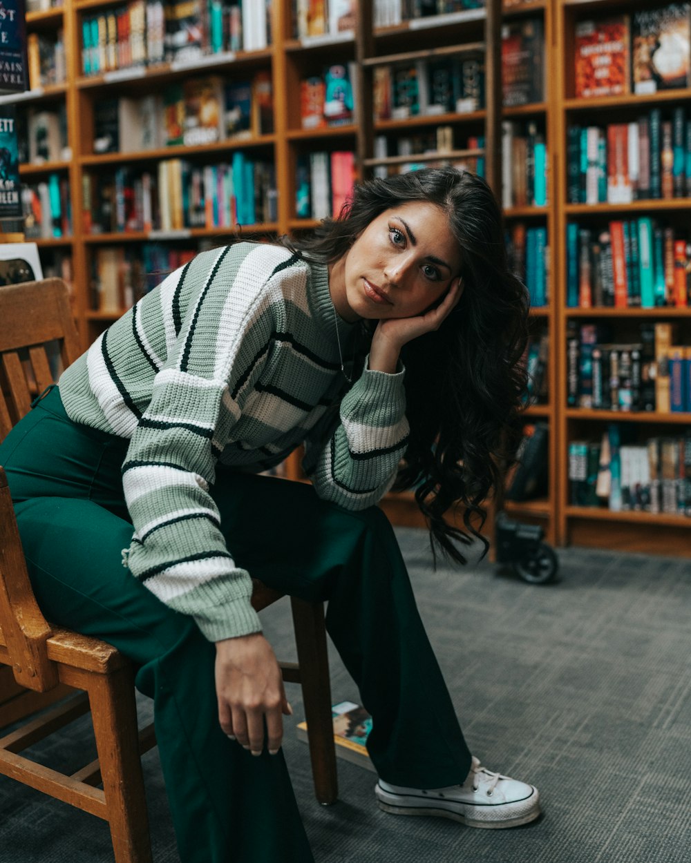 a woman sitting on a chair in front of a bookshelf