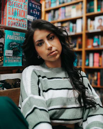 a woman sitting in a chair in front of a bookshelf