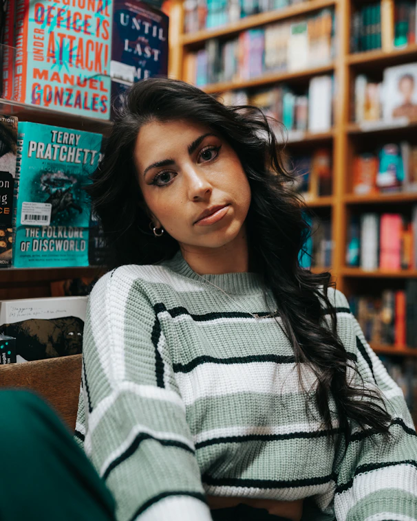 a woman sitting in a chair in front of a bookshelf