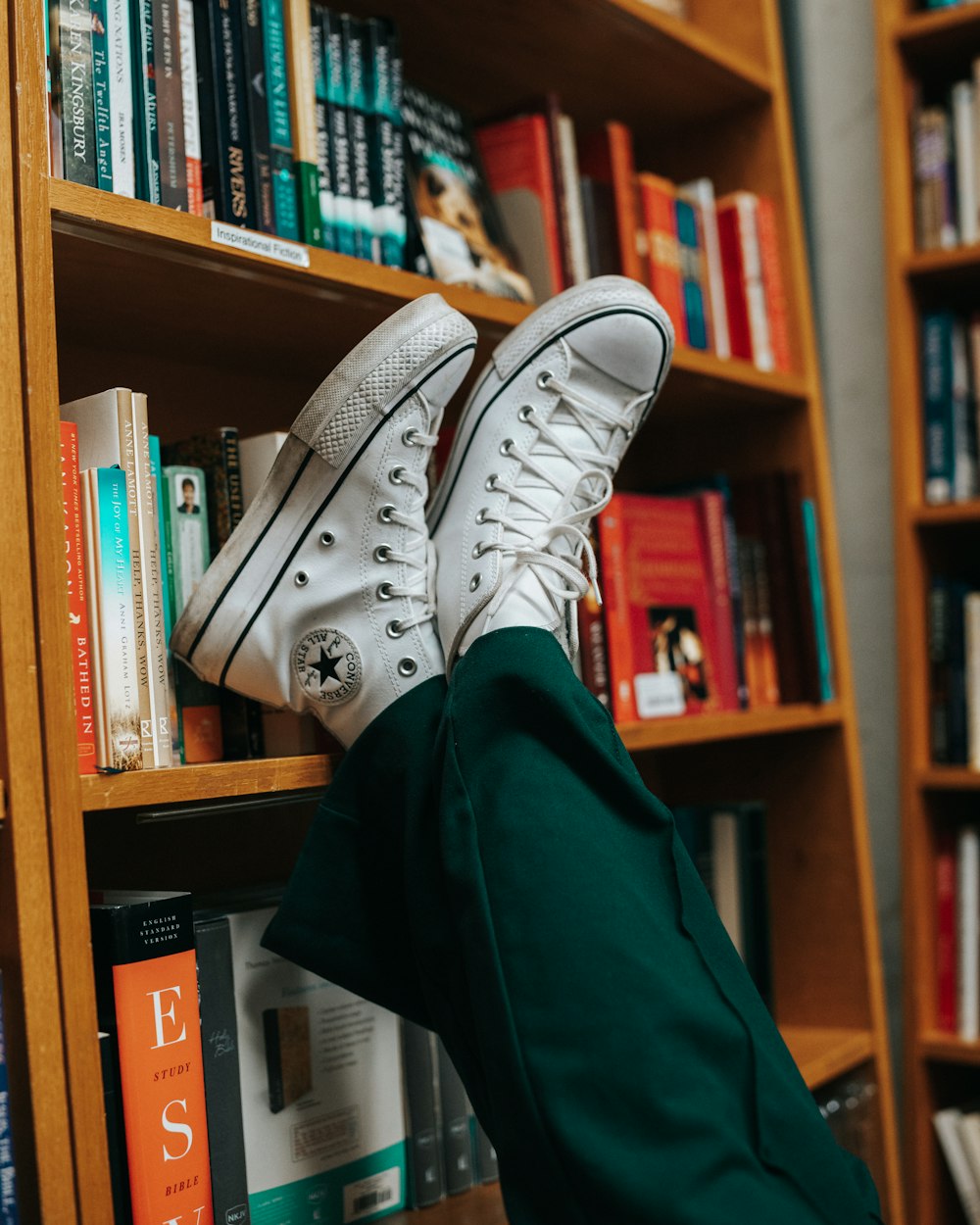 a person's feet resting on a book shelf in front of a bookshel