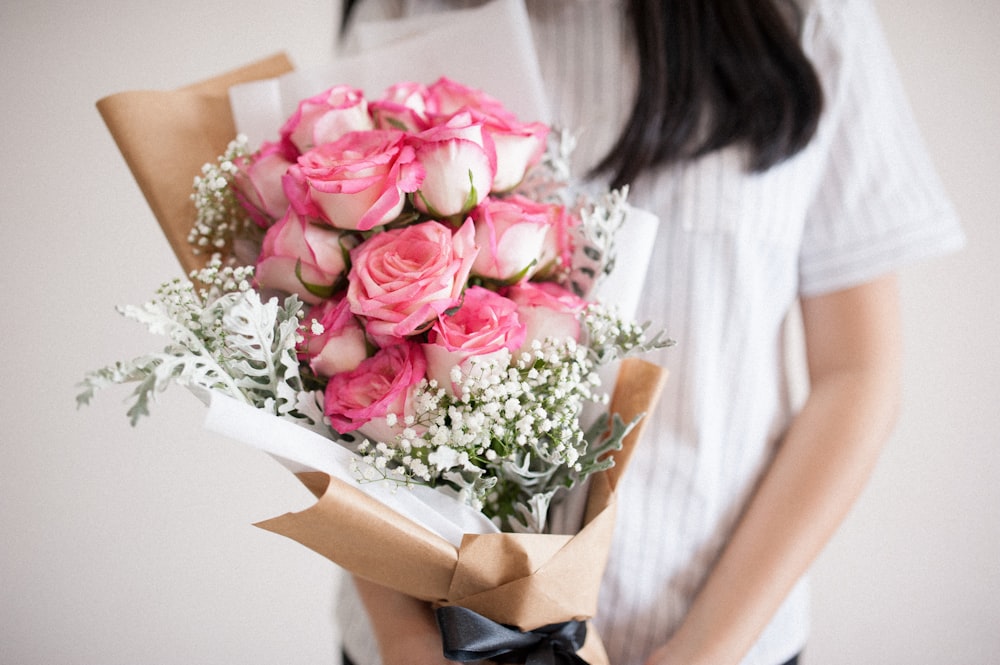 a woman holding a bouquet of pink roses