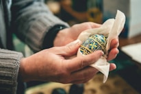 Close-up of hands holding a beautifully decorated Easter egg with soft natural light.
