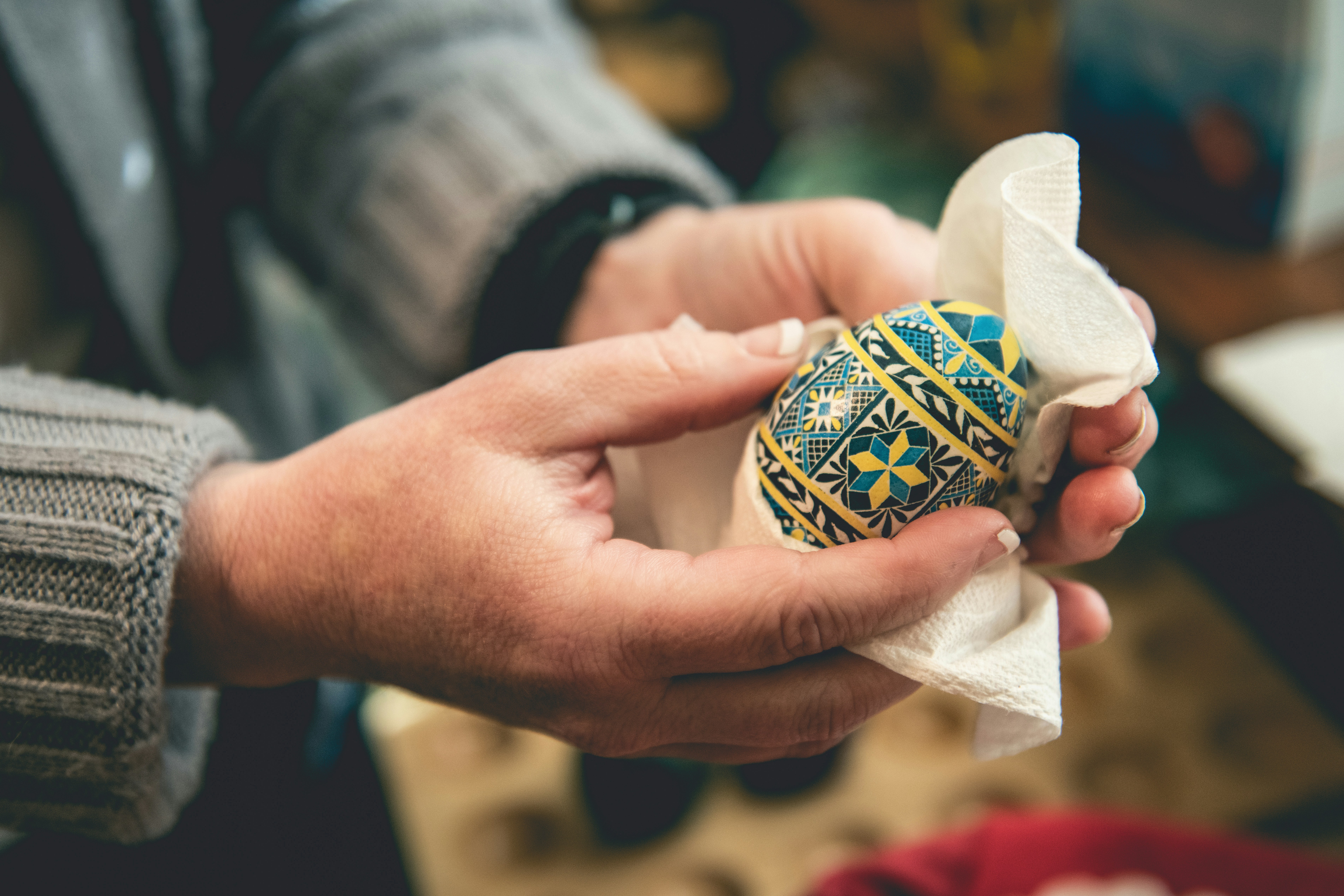 Hands holding a Ukrainian-style Easter egg in a paper towel, perhaps removing the wax.