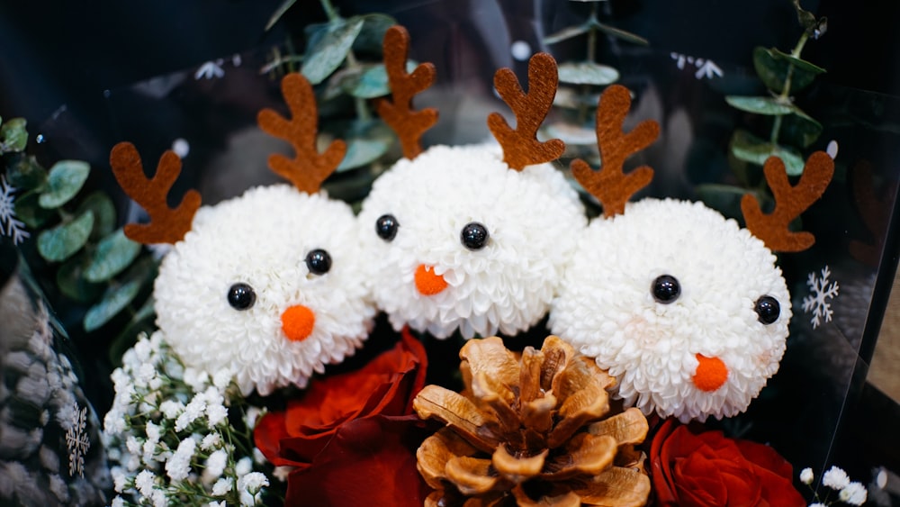 a group of snowmen sitting next to a pine cone