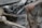 A scene of collapsed concrete structures with visible reinforcement steel bars and extensive rust. Debris and broken concrete slabs are scattered around, indicating a significant structural failure.