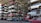 Numerous stacked rows of disassembled cars are placed on metal structures in what appears to be a scrapyard. Many of the cars are missing parts like wheels and doors.