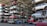 Numerous stacked rows of disassembled cars are placed on metal structures in what appears to be a scrapyard. Many of the cars are missing parts like wheels and doors.
