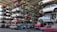Numerous stacked rows of disassembled cars are placed on metal structures in what appears to be a scrapyard. Many of the cars are missing parts like wheels and doors.