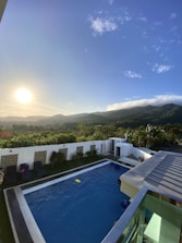 Outdoor private pool surrounded by lush green mountains at sunset.