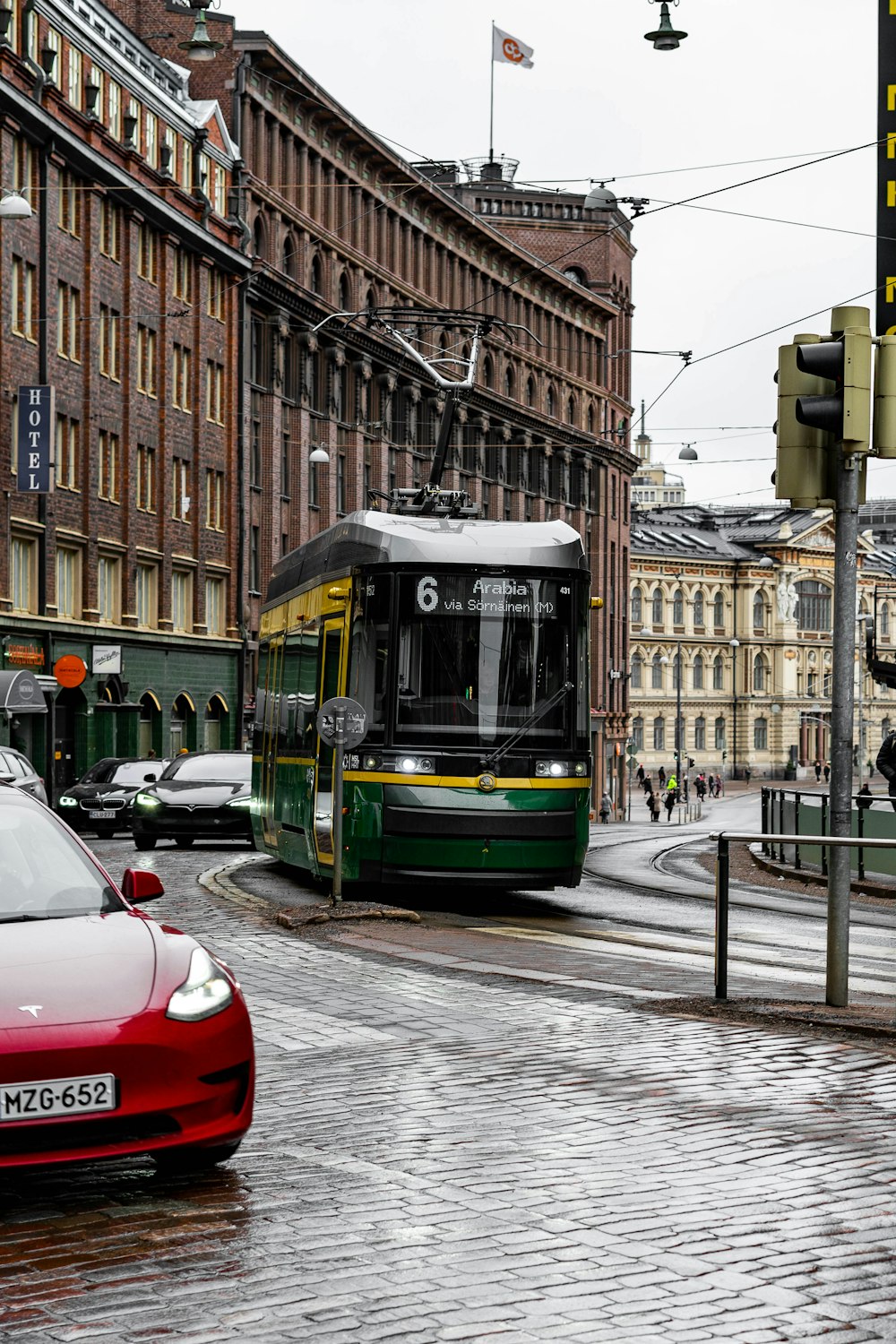a street scene with a red car and a green bus