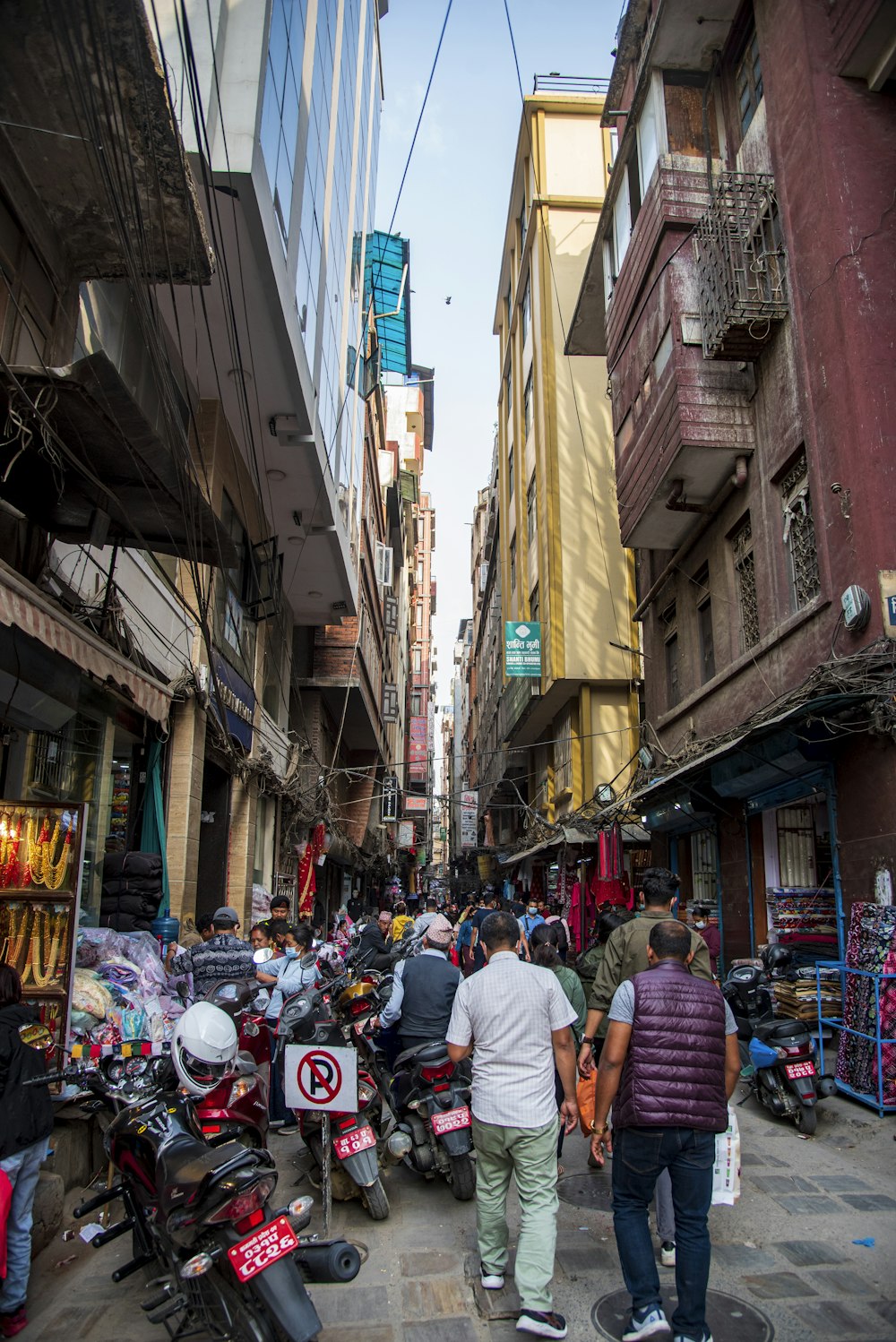 a group of people walking down a street next to tall buildings